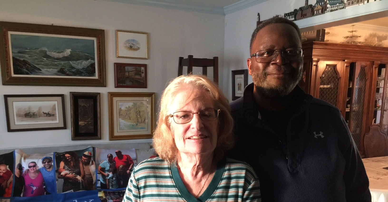 A middle-aged man stands with his arm around an older woman