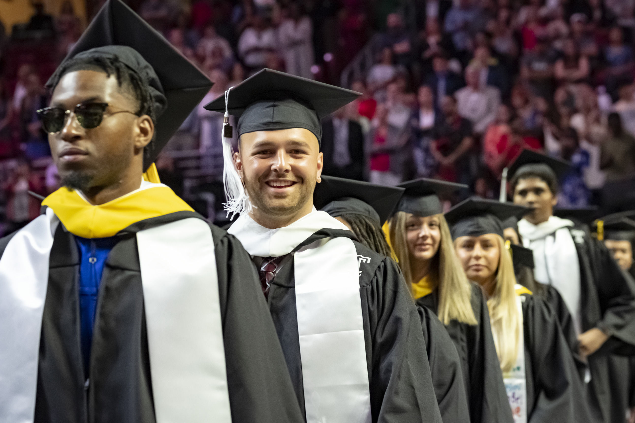 Graduating students in caps and gowns processing in Liacouras Center