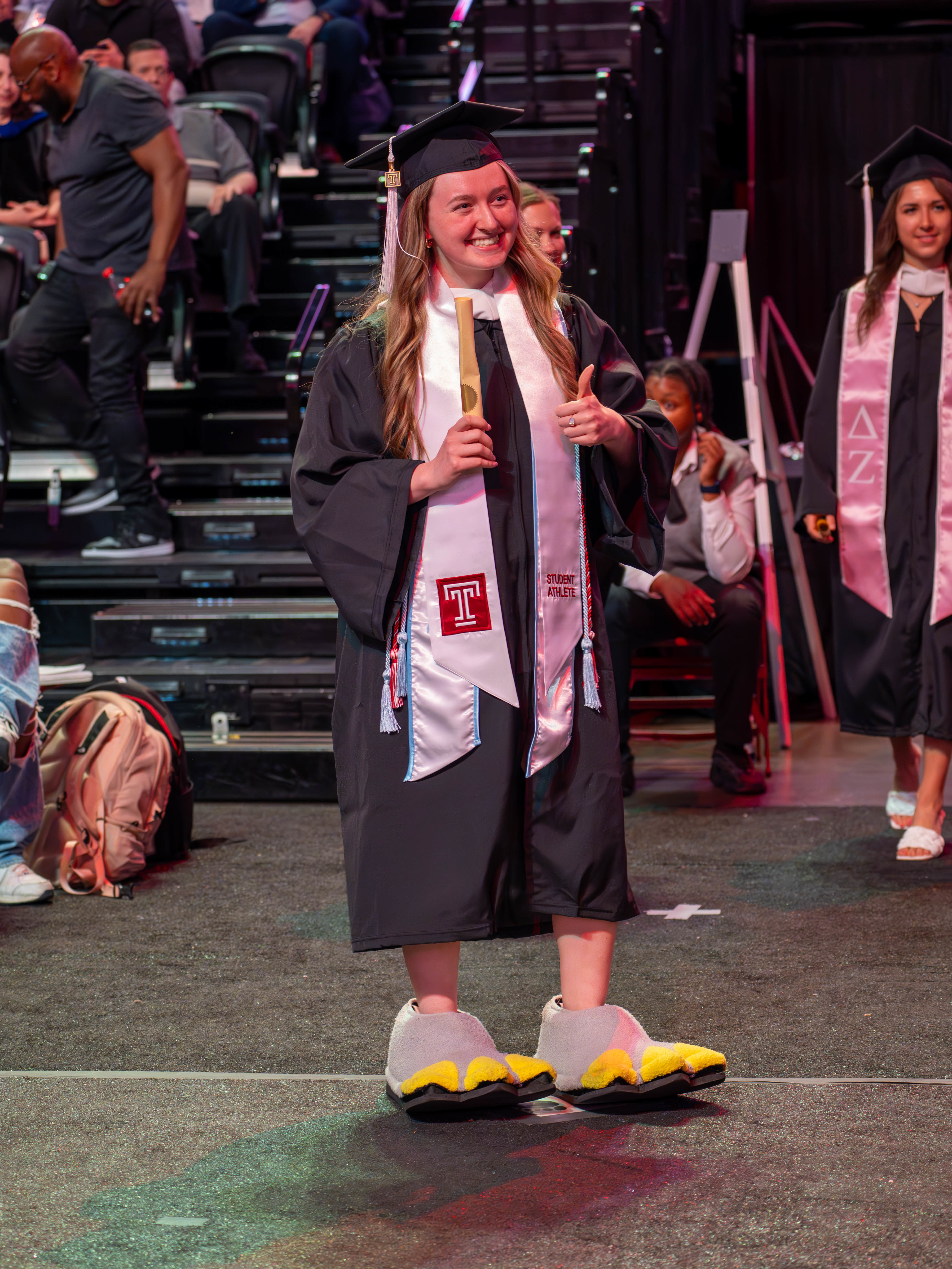 Graduate wearing "Hooter Feet" giving thumbs up after crossing the stage