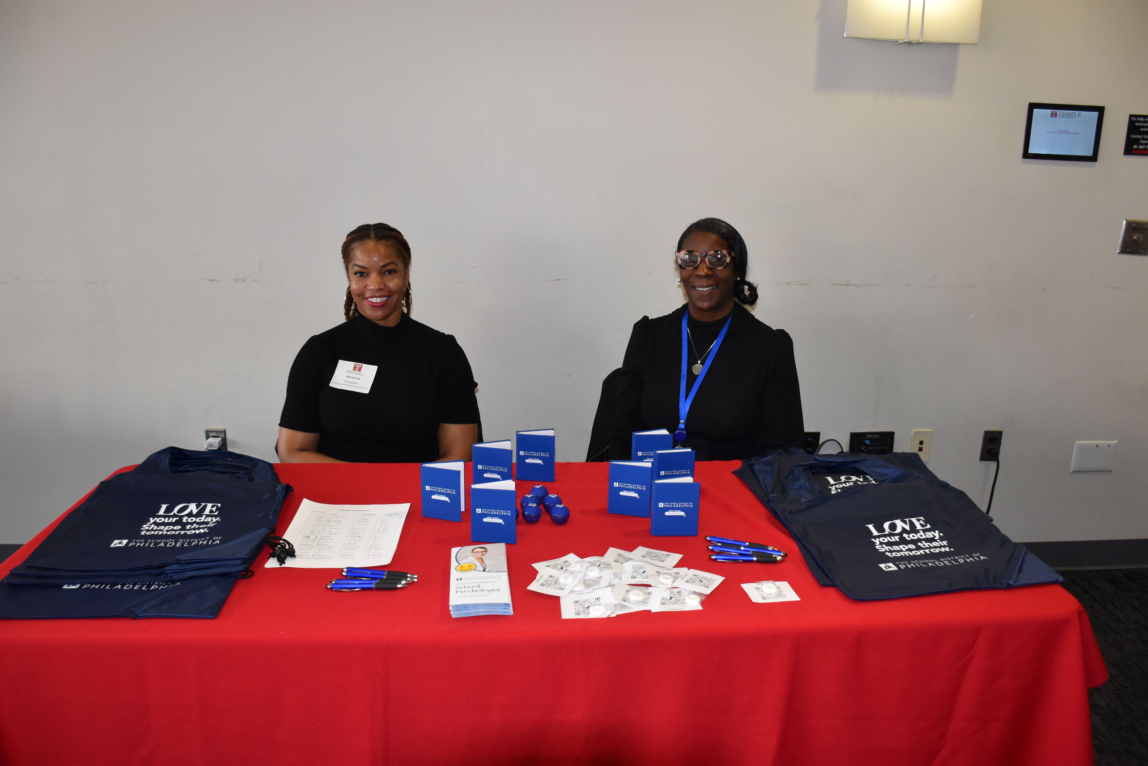 Two women sitting at covered table with giveaways