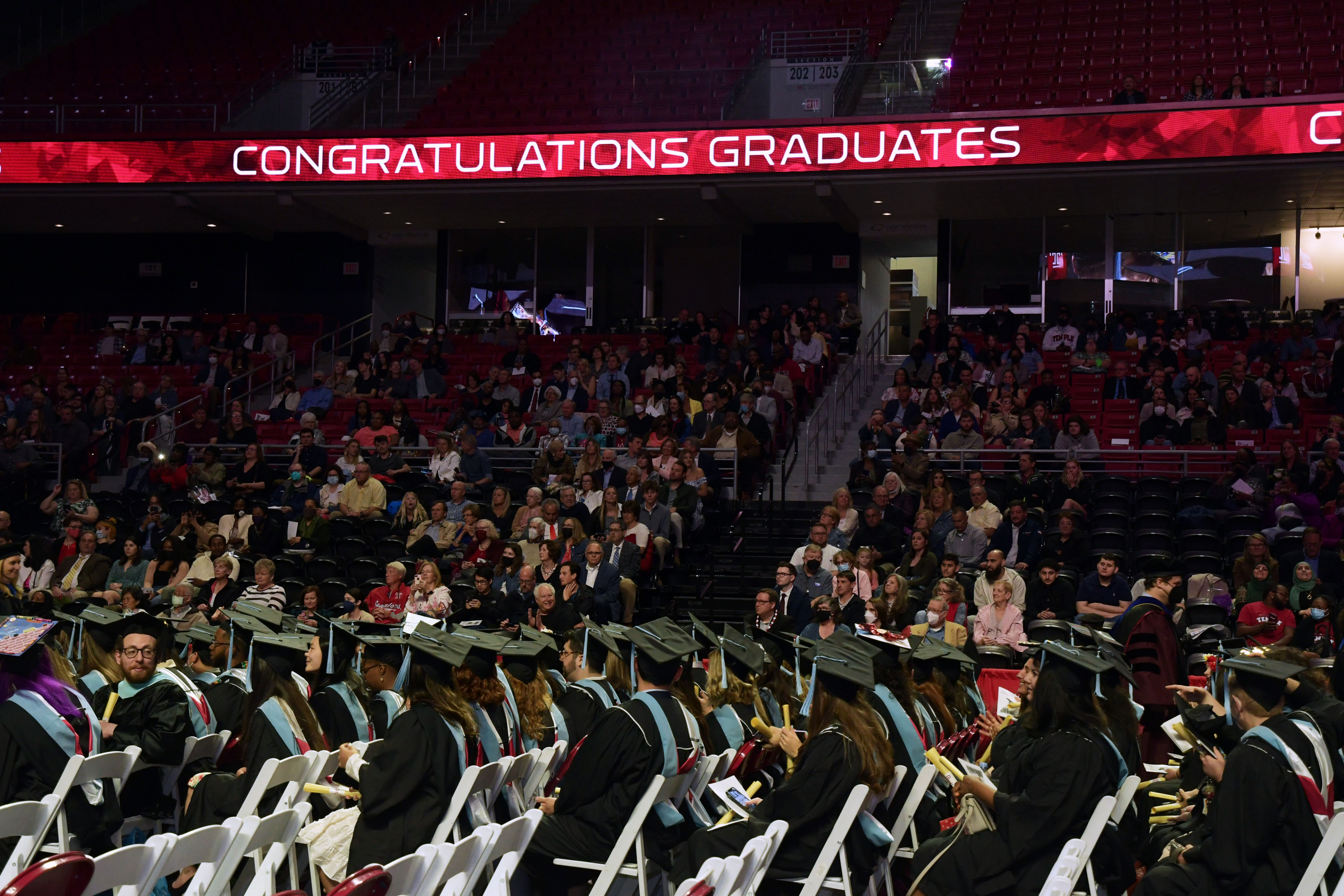 graduates in seats with electronic signage that reads "congratulations graduates"