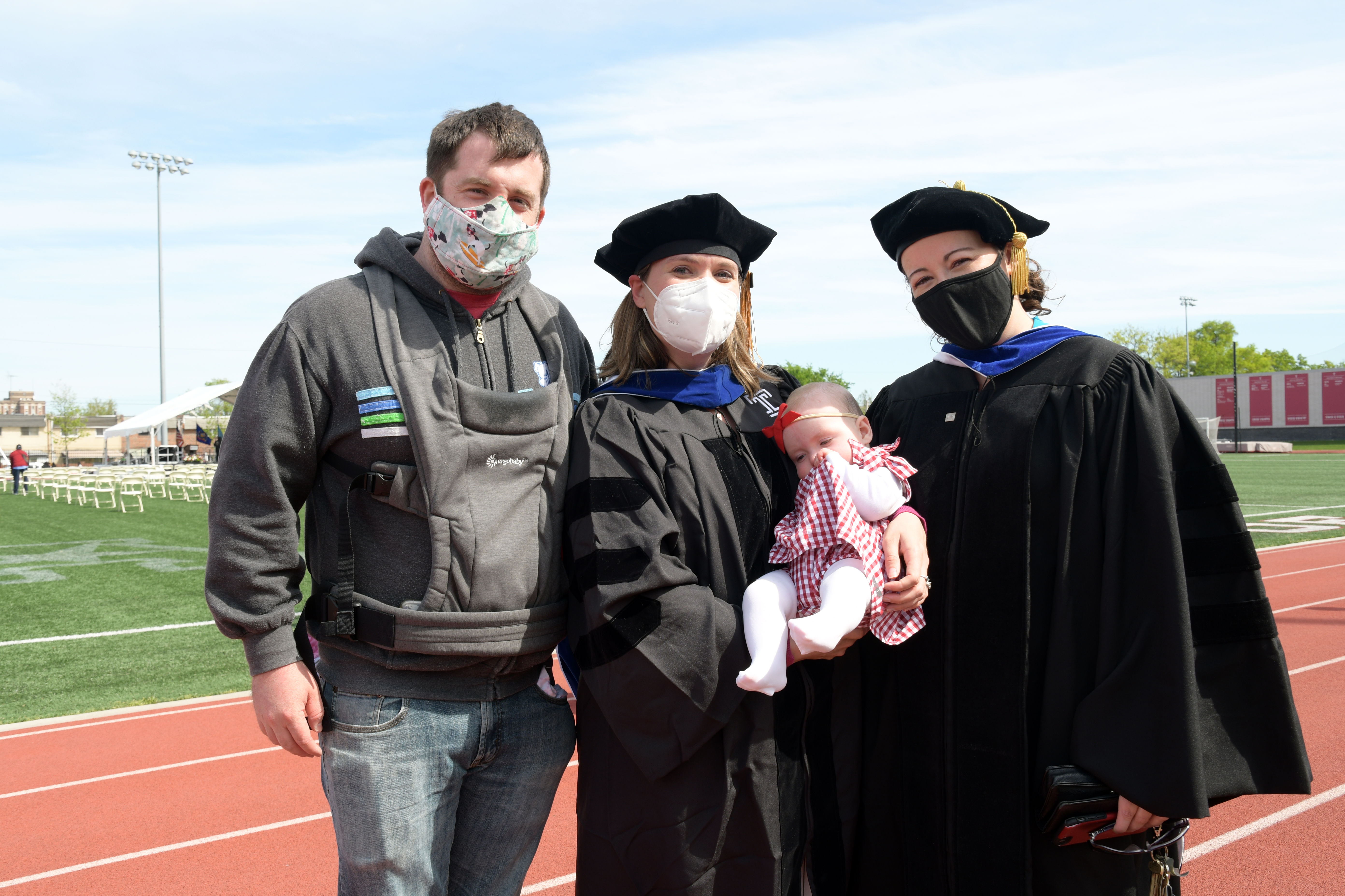 graduate holding a baby poses for photo with professor and family