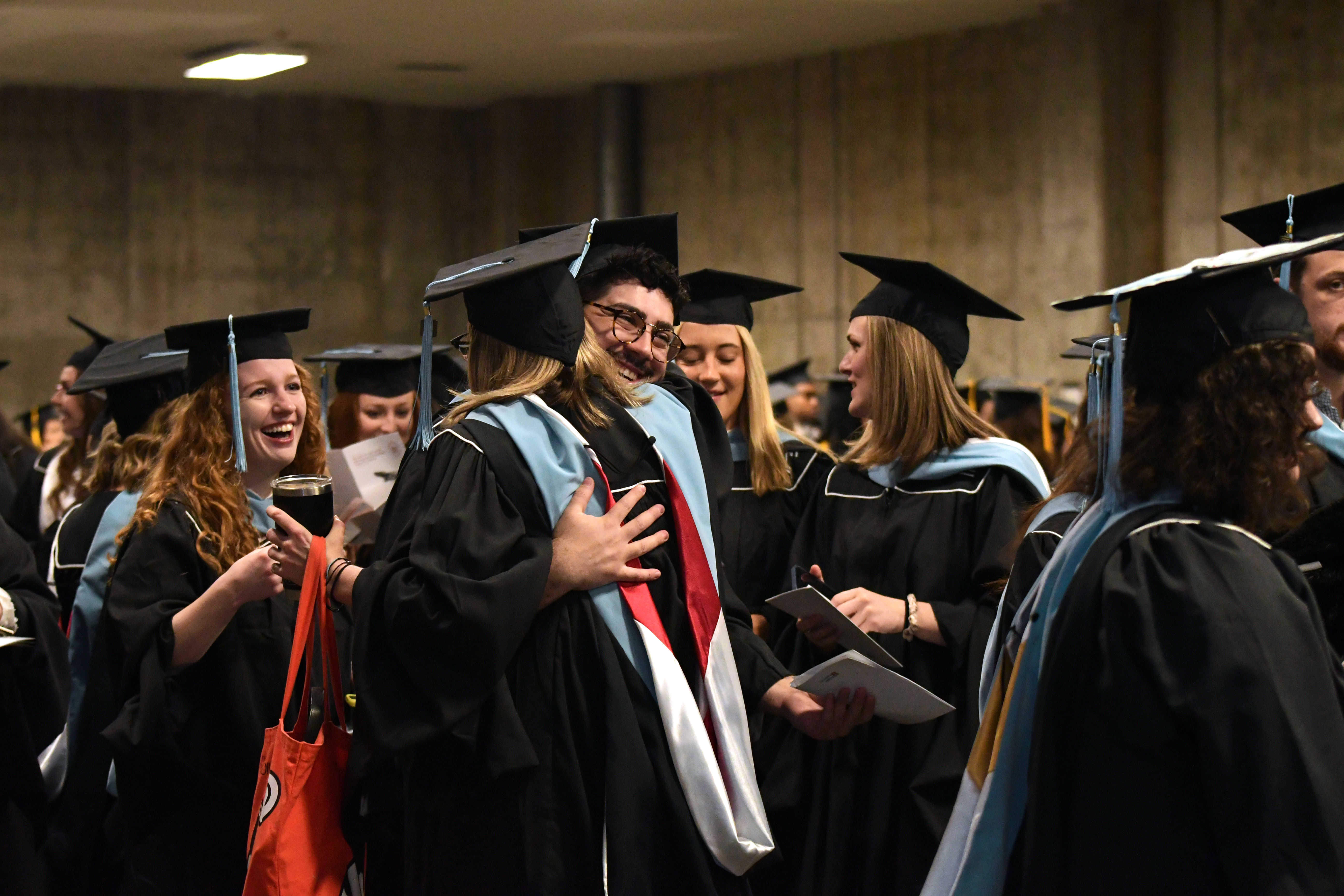 graduates embrace in the staging area