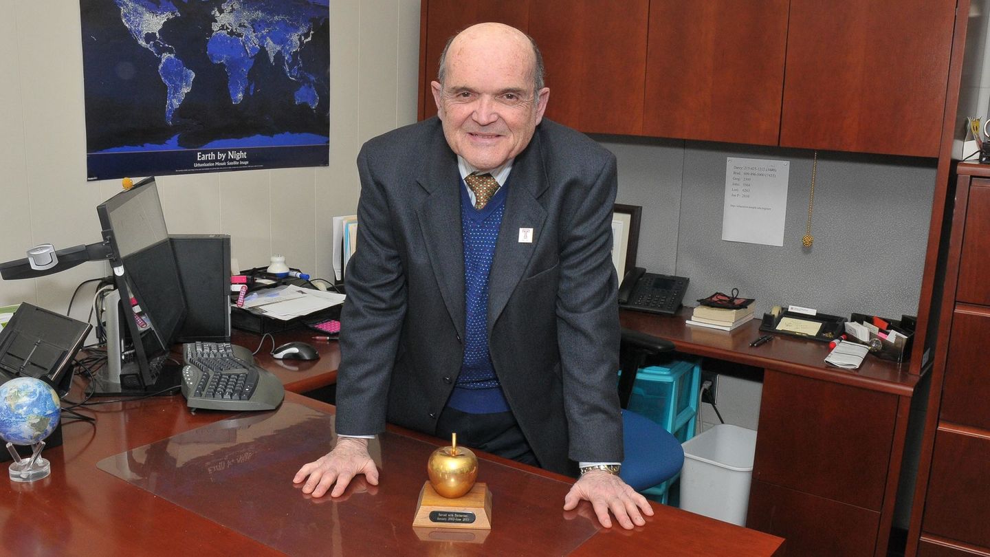 Joseph DuCette standing in his office at a desk with apple trophy on desk