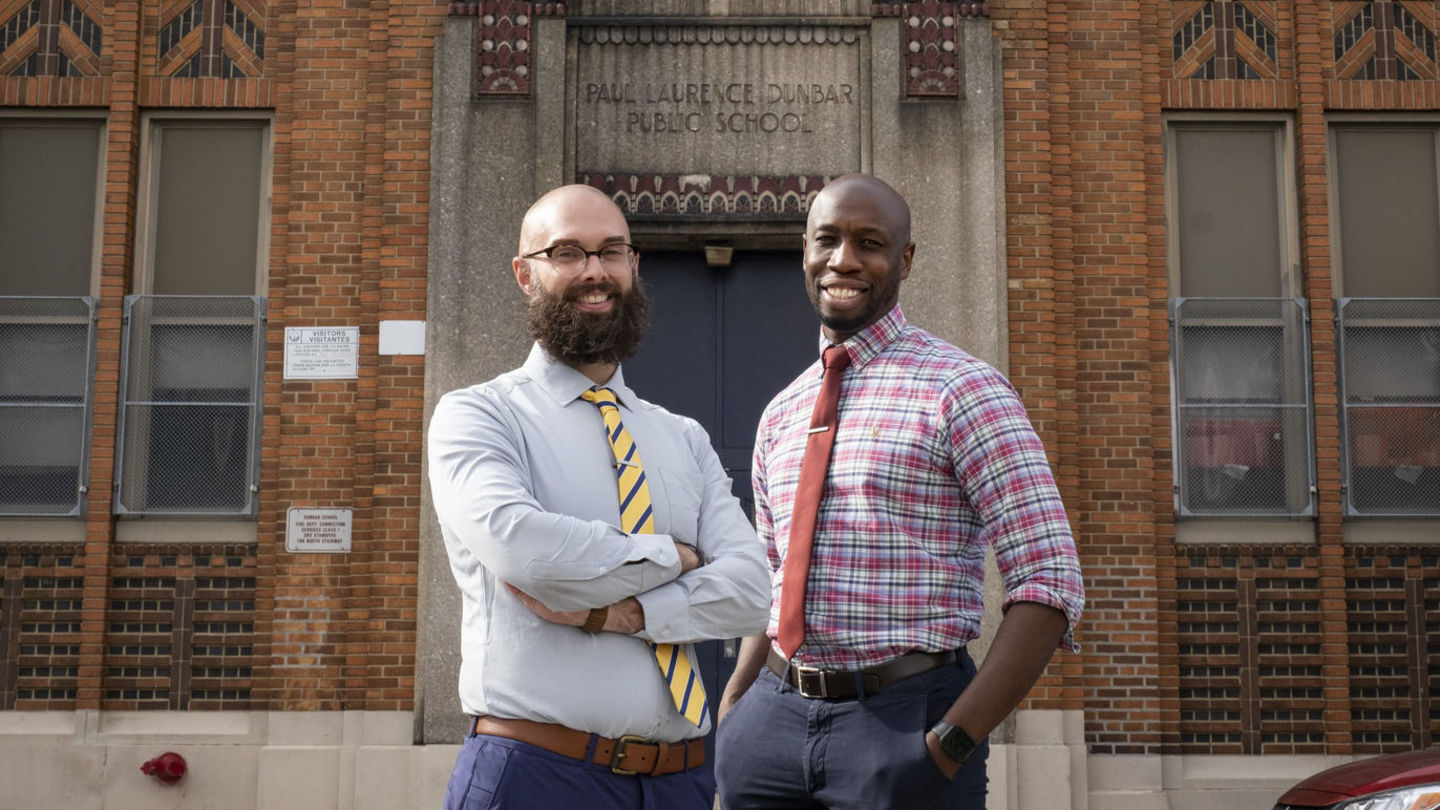 Daniel Mina, EDU ’14, and Justin Hall, CLA ’08, the principal and assistant principal of Paul L. Dunbar Elementary School, were childhood friends who met in eighth grade.
Image of the principal and assistant principal outside of Paul L. Dunbar Elementary School.