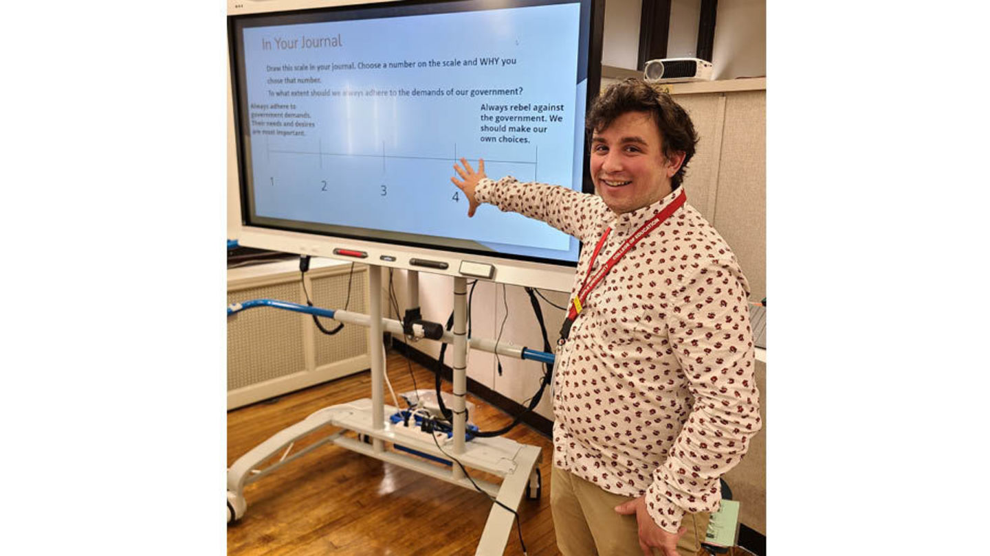 Graduate Student Eric Baker Eric Baker stands in front of a large digital monitor in a classroom