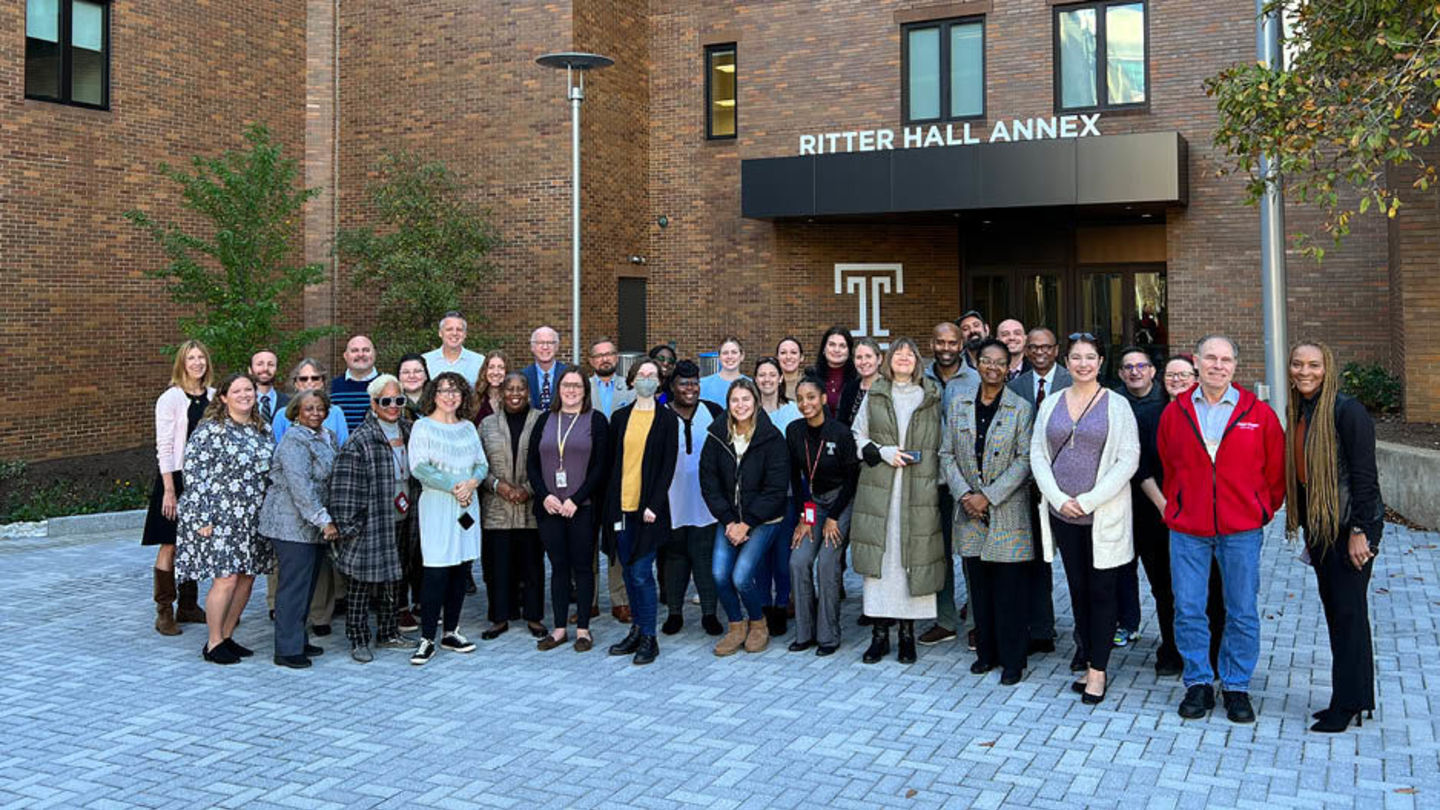 A large group of faculty and staff pose together outside of Ritter Hall