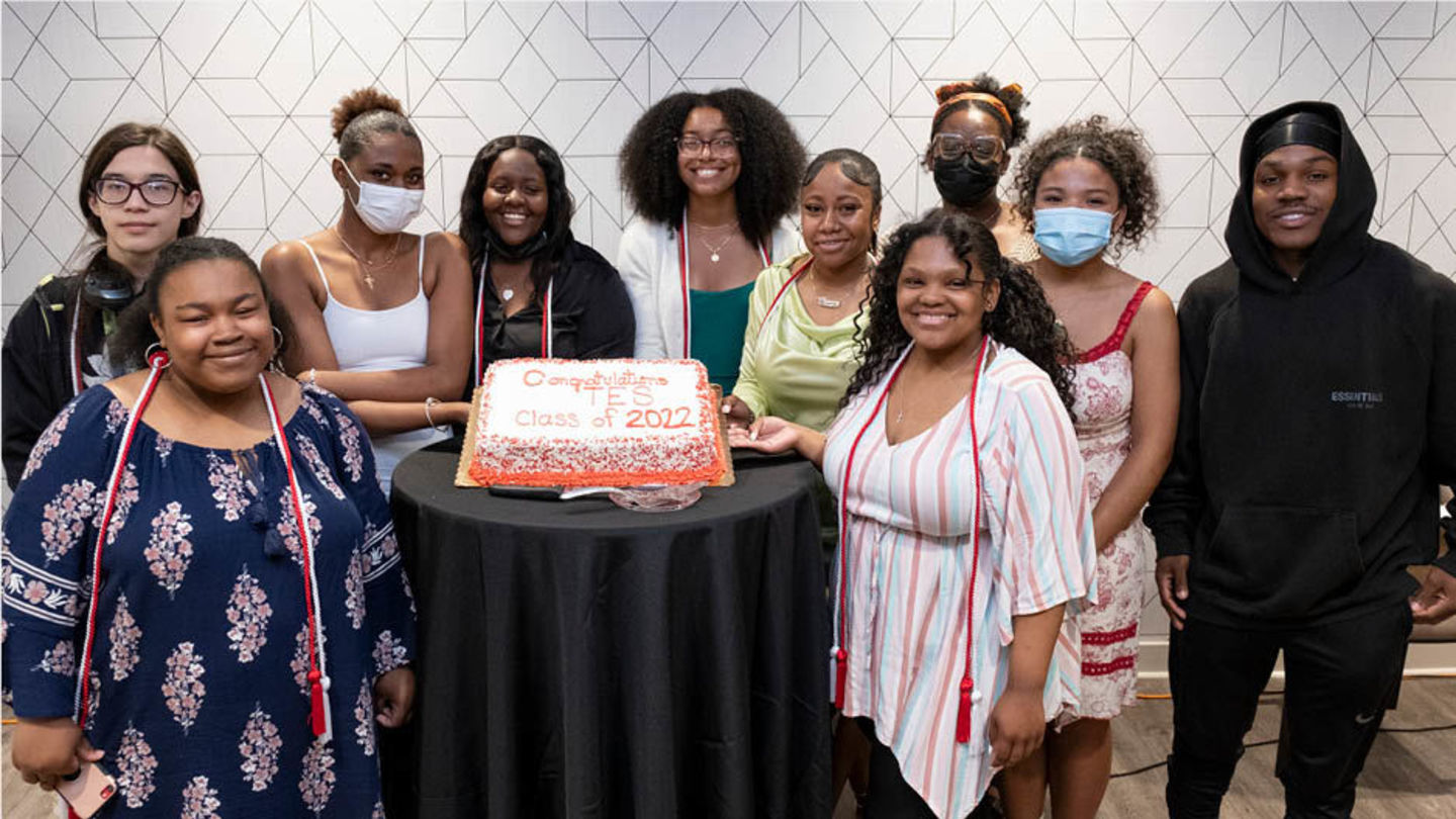 Group of TES participants pose for a photo around a cake