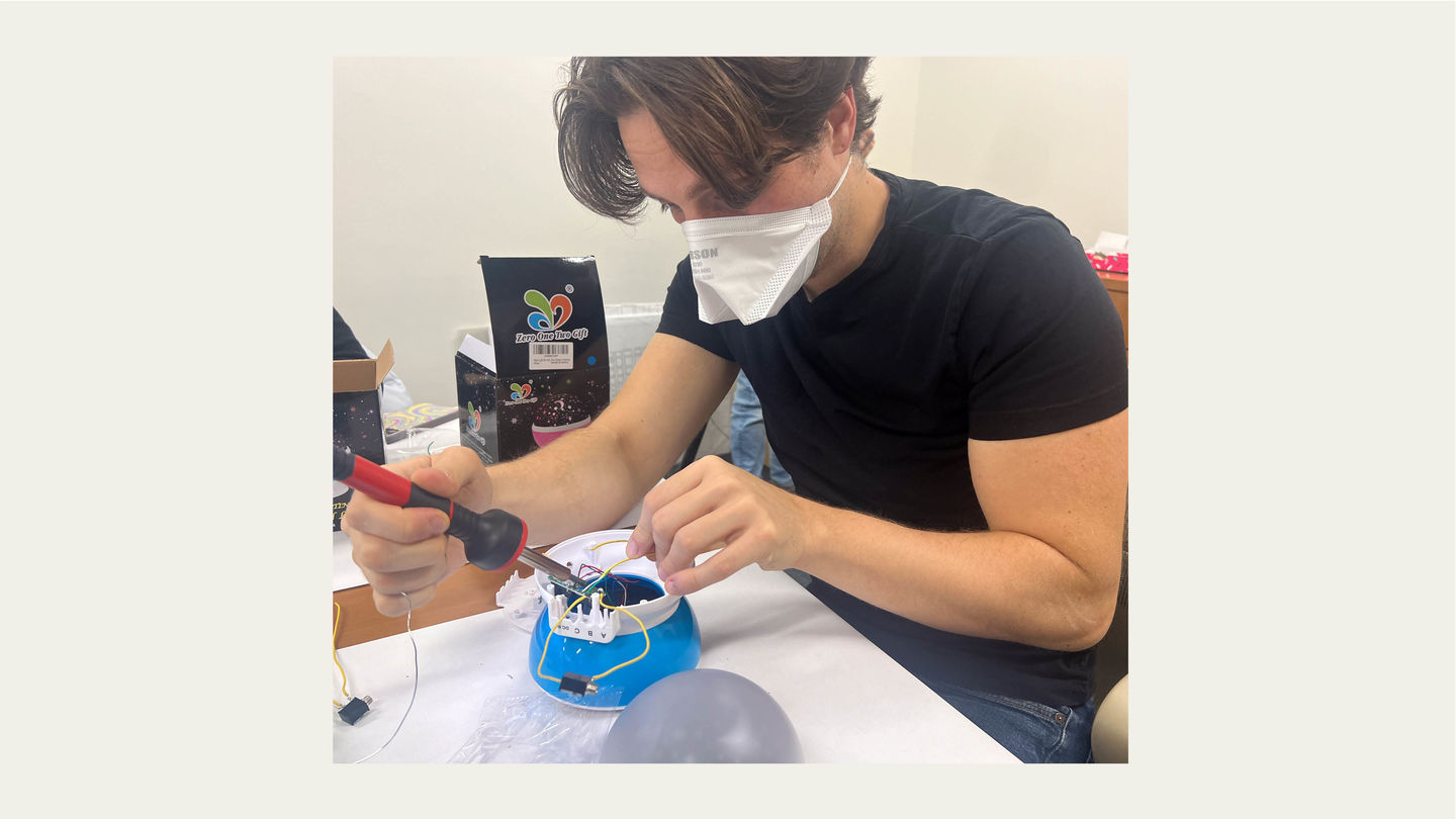 Tom from TechOWL soldering wires to a circuit board inside a plastic toy.