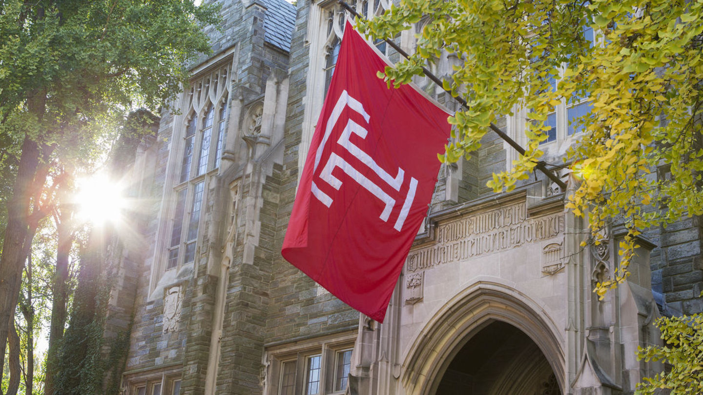 Large Temple flag hangs over entry to stone building, Sullivan Hall