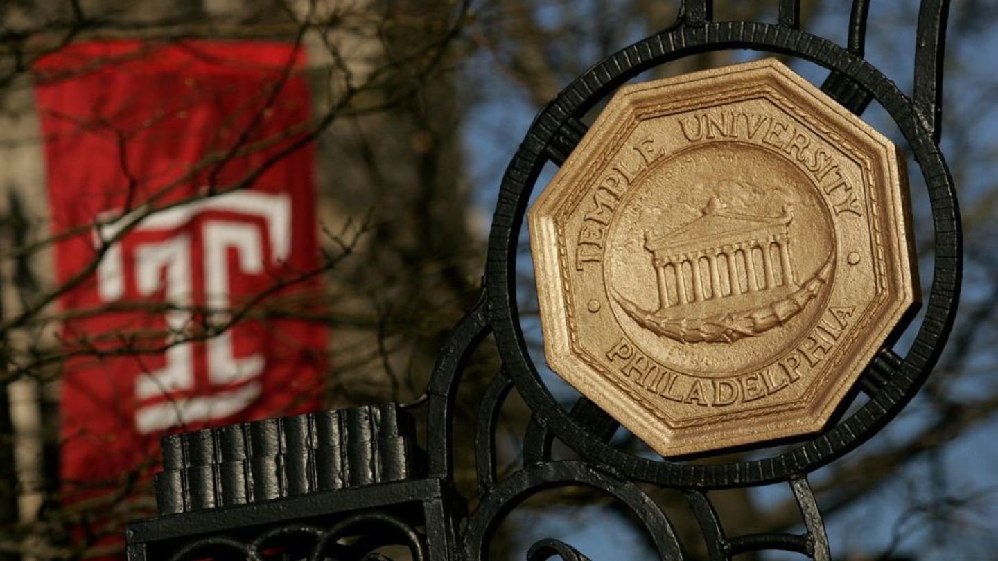 Iron gate with Temple University seal. A Temple T flag is in the background.