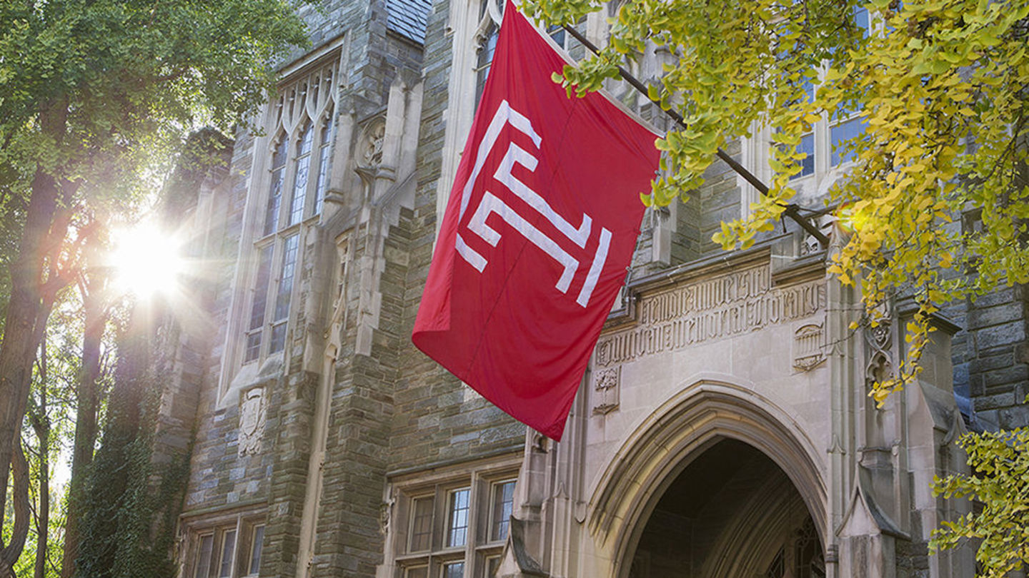 Large Temple flag hangs over entry to stone building, Sullivan Hall