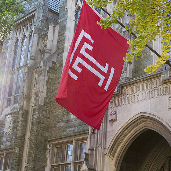 Large Temple flag hangs over entry to stone building, Sullivan Hall