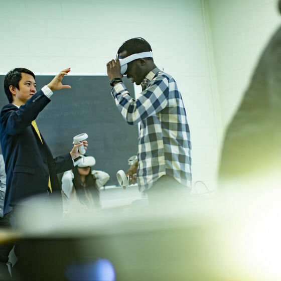 mage of Di Liu demonstrating virtual reality technology with teachers and students in a classroom.     