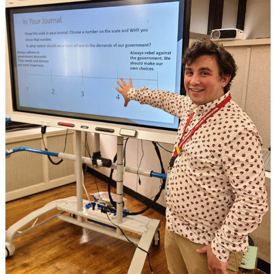 Eric Baker stands in front of a large digital monitor in a classroom