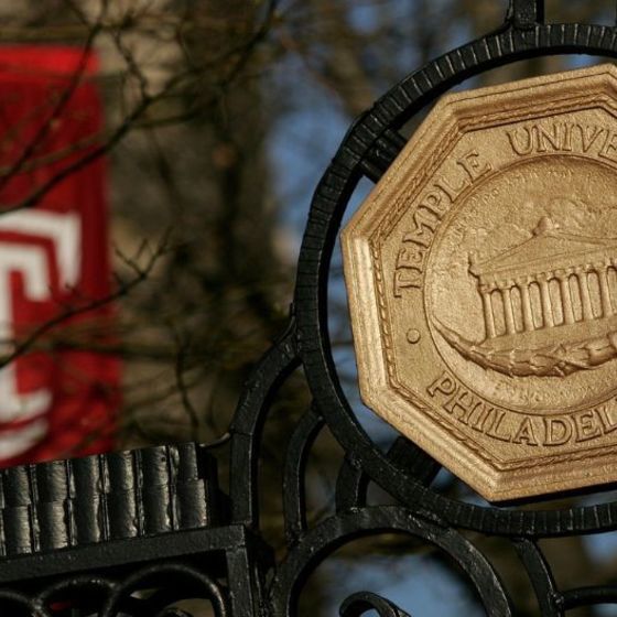 Iron gate with Temple University seal. A Temple T flag is in the background.