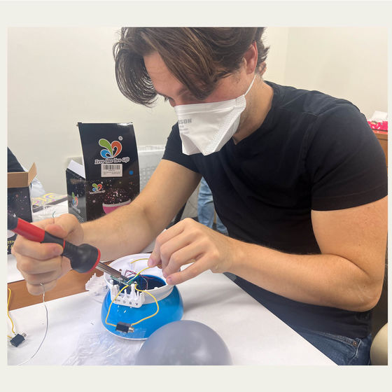 Tom from TechOWL soldering wires to a circuit board inside a plastic toy.