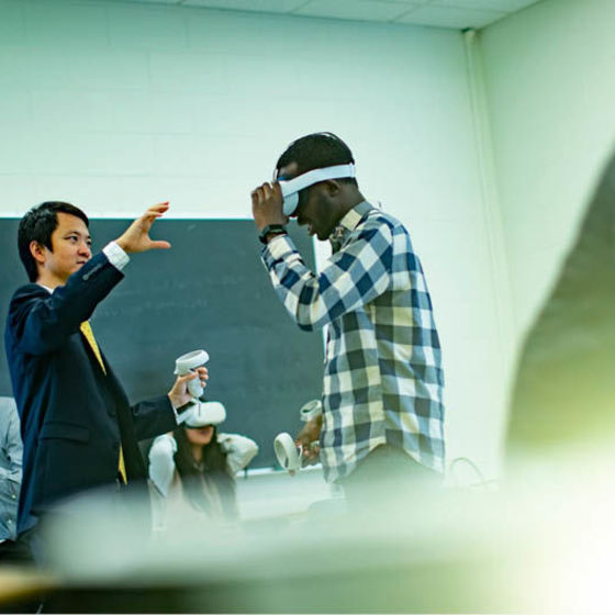 Professor Di Liu working with a student wearing a virtual reality headset during a demonstration